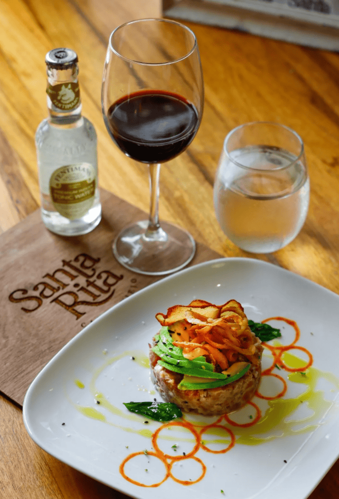 Plated dish at Santa Rita restaurant in Casco Viejo featuring tuna tartare with avocado, sweet potato crisps, wine, and sparkling water.
